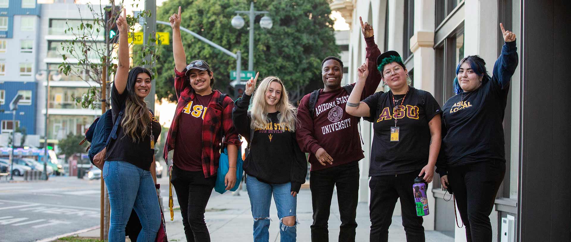 A group of people standing on a sidewalk Description automatically generated